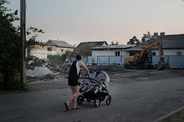 A man pushes a double baby buggy past the site on Mayakovsky Street where two houses destroyed by an explosion on the night of 3 July 2022. The Russian authorities claim it was caused by a Tochka-U ro...