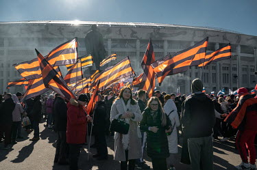 A crowd waving red and black St. George flags, which denote their support for Vladimir Putin, stand in front of a statue of Lenin at the Luzhniki stadium during a concert-rally dedicated to the eighth...