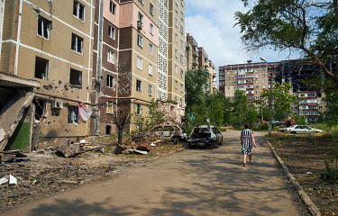 A woman walks past an apartment block destroyed by Russian shelling.
