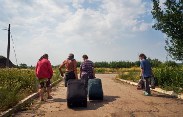 People helping take suitcases to a point from where their friends will be evacuated to safety. Due to extensive shelling, several people with their pet cats decided to leave for safety.