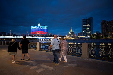 People walk along the embankment of the Moscow River.The letter 'Z', created by illuminating various offices in a government building, shine from a building on the far bank. 'Z' has become a pro-Putin...