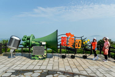 Taiwanese tourists stand by a statue commemorating a military radio station that used to broadcast Taiwanese music and propaganda in both Mandarin and the local Fujian Mindong dialect across the narro...