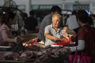An elderly man buys pork at a wet market.