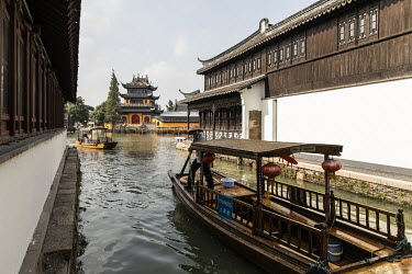 A man paddles a traditional wooden boat along a canal in the Zhujiajiao Water Town in Shanghai. Zhujiajiao is one of several canal based towns in the Yangtze Delta region that many tourists visit.