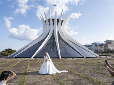 A bride is photographed in front of the Metropolitan Cathedral, or Cathedral of Brasilia, designed by Oscar Niemeyer.
