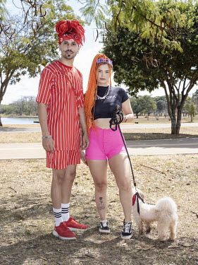 A young couple, sporting colourful hair extensions, with a dog in the Sarah Kubitschek City Park.