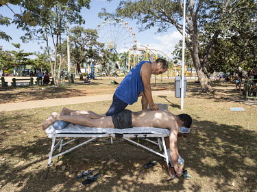 A man has an outdoor massage in the Sarah Kubitschek City Park.