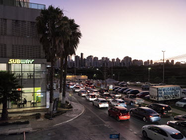 Heavy traffic on a road in Aguas Claras, an upscale district of Brasilia, characterised by gated high-rise residential buildings.
