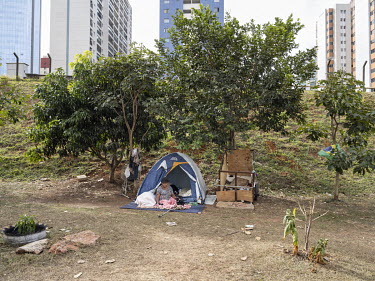 A homeless woman living in a tent in Aguas Claras, an upscale district of Brasilia, characterised by gated high-rise residential buildings.