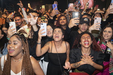 Fans take out their mobile phones and scream as the popular Brazilian rapper Delacruz takes the stage at Complexo Fora do Eixo.