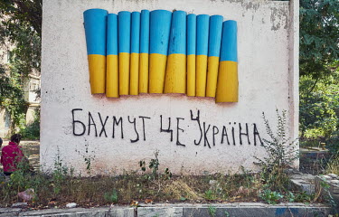 A graffiti that reads Baxmut tse Ukraina (Bakhmut is Ukraine) on a concrete wall under the concrete Ukrainian flag.Â�
