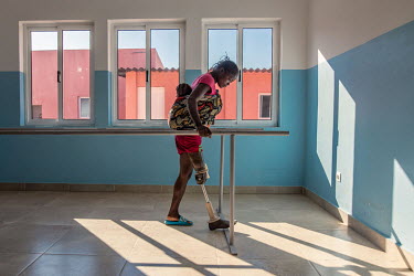 Magdalena Manuel, 30, carries her child as she practices walking with a new prosthetic leg at the Princess Diana Orthopaedic Centre. Manuel lost her leg after triggering a landmine on the way back fro...