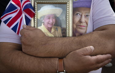 A man hugs two framed portraits of Queen Elizabeth II on the first day of the reign of King Charles lll, as members of the public gather outside Buckingham Palace to mark the death of Her Majesty the...