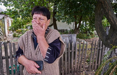 A woman watching a burning house across the street. a Just a short while earlier a plane coming from the so-called Donetsk People's Republic dropped a bomb on the private house. There were no casualti...