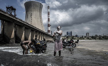Locals wash themselves and their motorbikes in the shadow of the Bokaro Thermal Power Plant on the Konar river, a tributary of the Damodar.Experts say river pollution poses a grave threat to India's h...