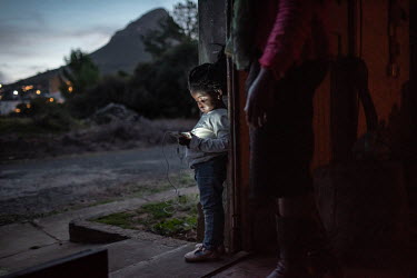 Lillian Mvolontshi and her granddaughter, Phawu watches a video on a phone screen in the abandoned military warehouse where their family now live in central Cape Town. While living in the township of...