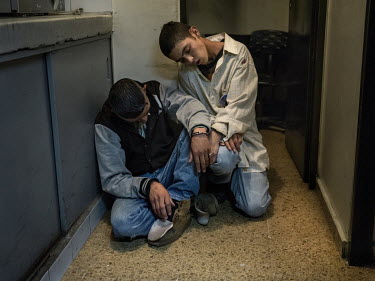 Two young boys in an intoxicated narcotic sleep, slumped on the floor of a house after being arrested by the police for street fighting.