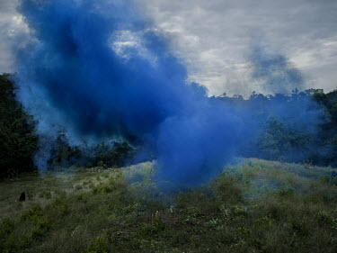 Blue smoke marks the landing spot for a military helicopter during a search and destroy mission at a coca plantation.