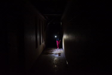 A resident uses a torchlight to navigate along a dark corridor in Ahmed Kathrada House, an abandoned nursing home in central Cape Town that has been occupied by a community of several hundred evictees...