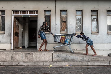 Two girls push a shopping trolley full of buckets of water to their family's rooms in Ahmed Kathrada House, an abandoned nursing home in inner-city Cape Town that has been occupied since 2017 by a com...