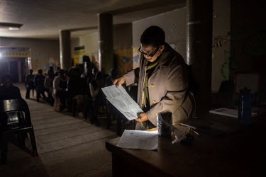 Community leader Shiela Madikane uses a battery powered light to read through the agenda during a meeting at Ahmed Kathrada House, an abandoned nursing home in central Cape Town that has been occupied...
