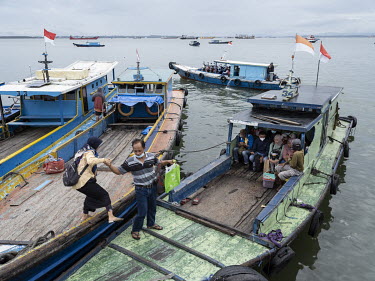 A man helps a woman embarking a wooden ferry boat moored in Balikpapan Bay, in Kampung Baru. Balikpapan Bay is a gateway to the new Indonesian capital, Nusantara, that will be built at the northern ti...