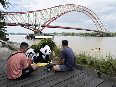 Two men with soft toy panda bears relaxing on the banks of the Mahakam river.In 2019, President Widodo announced the plan to move the Indonesian capital from Jakarta, plagued by overcrowding and flood...