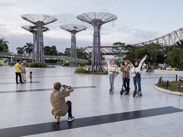 Three women riding scooters are photographed in front of man-made 'trees' in Kota Raja Park on the Mahakam river banks. Tenggarong, capital of Kutai Kartanegara Regency, is located near the site of th...