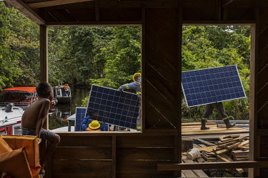 Workers, from a company responsible for assembling photovoltaic solar panels in rual communities, unload the equipment to be installed in a remote community located on a creek on Marajo Island. The ri...