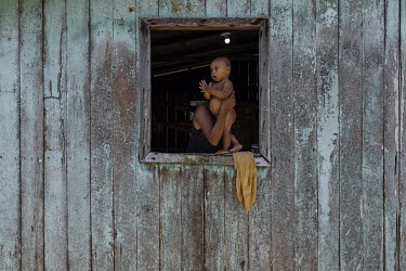 A child looks on from the window as workers, from a company responsible for the installation of photovoltaic solar panels, assembles equipment in the house of the dos Santos Alho family which is locat...