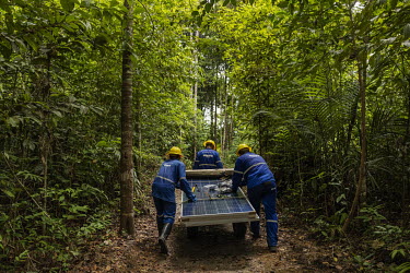 Workers, from a company responsible for assembling photovoltaic solar panels in rual communities, transport the equipment to be installed through the forest to a remote community located on a creek on...