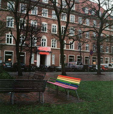 A park bench decorated in the Rainbow Pride flag colours.