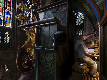 Organist Pascal Reber, and his colleague Guillaume who helps him to turn the pages and change the levers of registers, during a Sunday mass on the great organ of Strasbourg Cathedral.