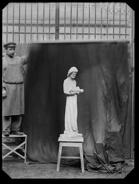 This is probably a sculptor from the Fondation de l'Oeuvre Notre-Dame posing in front of a statue of a musician in the large gable of the central portal. Photo taken between 1890 and 1920.~~( Archive...