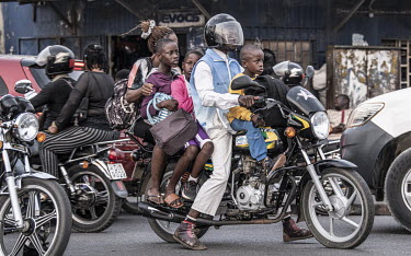 A man carries a woman and three children on a motorbike as they negotiate a busy city street.As motorcycle ownership in sub-Saharan Africa has grown from less than five million in 2010 to an estimated...