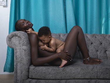 Stella, a 19 year old mother, lies naked on a couch breastfeeding her son. She met the boy's father on an internet dating site.
