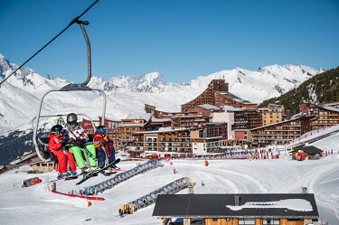 Tourists in a ski lift, with the Arc 2000 resort in the background.