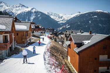 Tourists ski past chalets in a resort.The impact of global warming is becoming increasingly evident, as seen in the drop in snowfall levels in the Alps. On average, snowfall levels have decreased by 6...