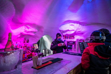 Dinosaurs, carved from ice, decorate a bar made in an igloo where tourists can take a break from the slopes to order a drink or, for a fee, simply admire the ice sculptures.To attract more tourists, s...