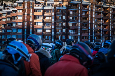 People waiting for a ride on a ski lift. In the background is a multi story accomodation block.To attract more tourists, ski resorts are expanding their offerings beyond traditional skiing activities...