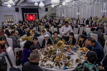 Guests enjoying food and drink at a wedding reception. The wedding party is seen by many Kazakhs as an indicator of social status. Showing off one's economic success is paramount. The aim is to win th...