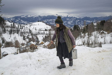 An elderly woman carrying some milk in a pewter container. High in the mountains above Poienile de sub Munte, said to be Romania's largest village, is an unnamed community of smallholders that some ca...