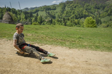 A boy rides down a hill on a homemade wheeled toy.High in the mountains above Poienile de sub Munte, said to be Romania's largest village, is an unnamed community of smallholders that some callDardila...