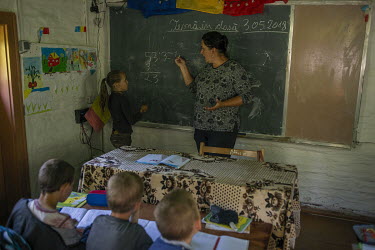 A teacher shows a pupil a maths solution. The village has a small school with one class attended by children in years 1-4.High in the mountains above Poienile de sub Munte, said to be Romania's larges...
