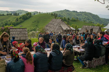 People sit down to eat a meal at the funeral of Miron Ghibus, who died aged 82 years old. Ghibus had been living and working in the forest his entire life. He was said to have been a kind and friendly...