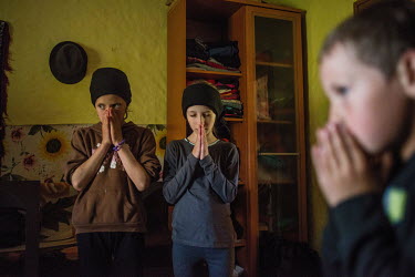 Little girls praying during a funeral service.High in the mountains above Poienile de sub Munte, said to be Romania's largest village, is an unnamed community of smallholders that some callDardila's H...