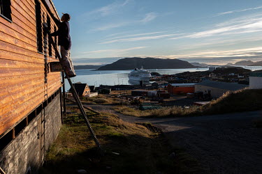 Paul Cohen, left, staining the wooden exterior of one of his homes. Originally from the USA, Paul and his German wife Monika moved to Greenland decades ago. Working remotely as a translator, Paul and...