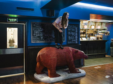 A woman standing on a model bear in the only bar in Barentsburg which is also home to the world's northernmost brewery.