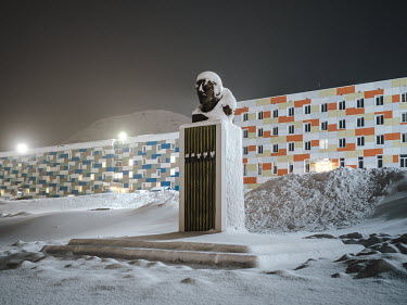 A bust of Lenin stands in front of residential buildings mainly housing single occupants in two prefabricated buildings. The buildings were renovated a few years ago and clad with colourful facades.