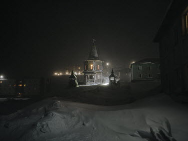 The northernmost Russian Orthodox Church surrounded by snow and illuminated in the polar night.